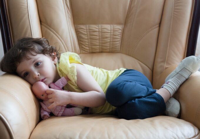 Afraid preschooler curled up in chair shows impact of anxiety in young kids