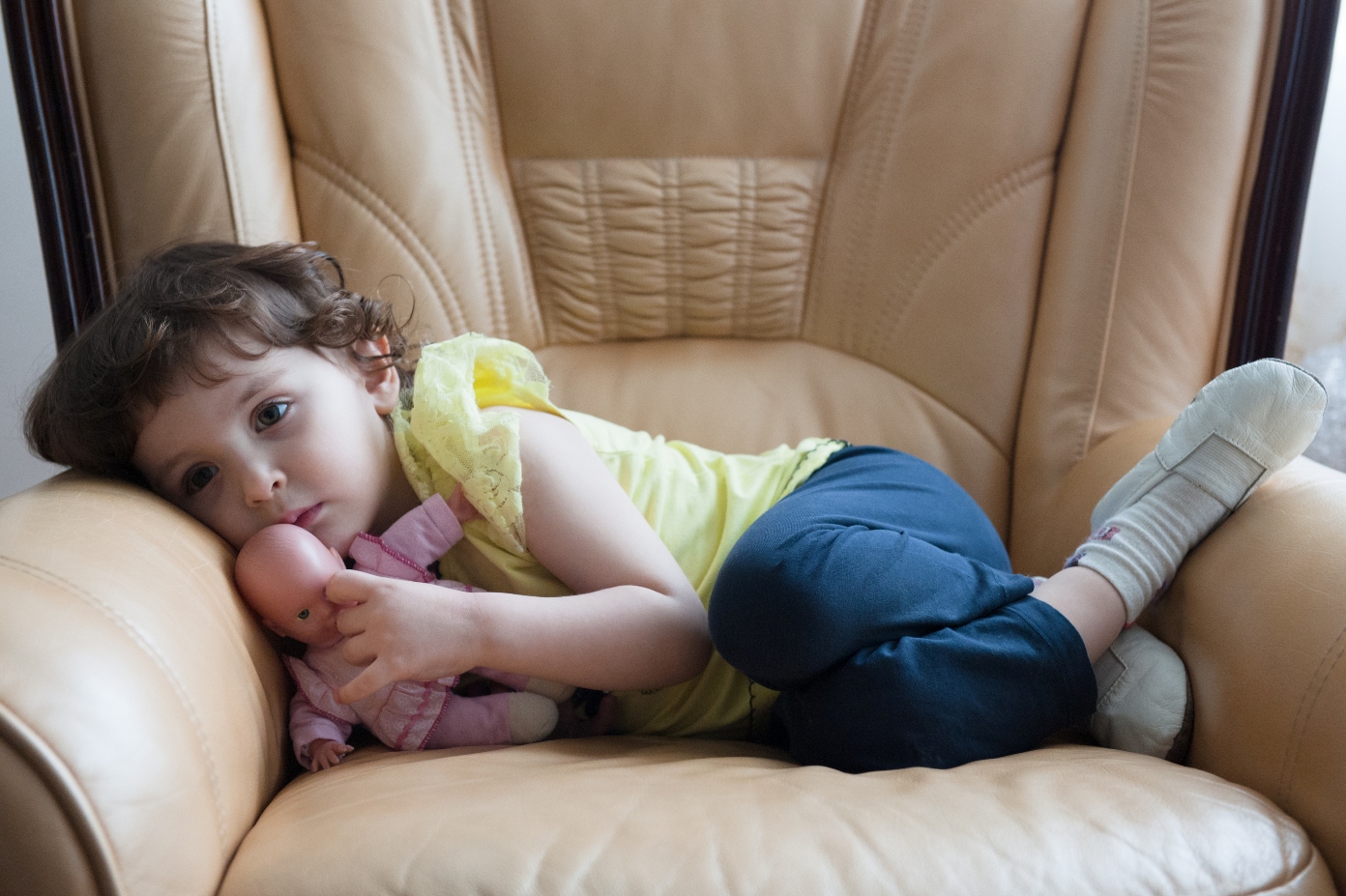 Afraid preschooler curled up in chair shows impact of anxiety in young kids