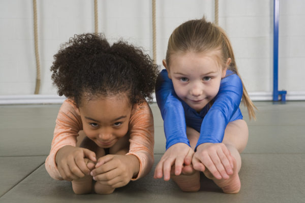 Two little gymnasts stretch to avoid back pain