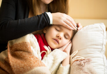 Mom feeling forehead of daughter with fever