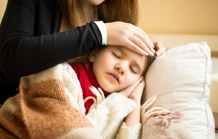 Mom feeling forehead of daughter with fever