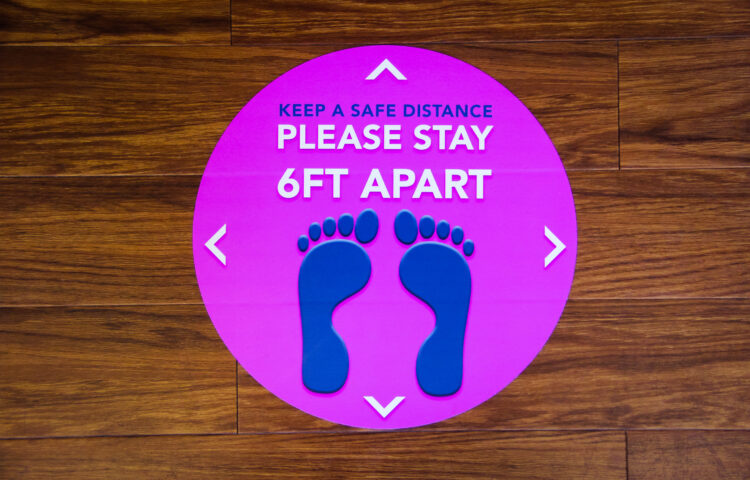A sticker on the floor reminding people to stay 6 feet apart