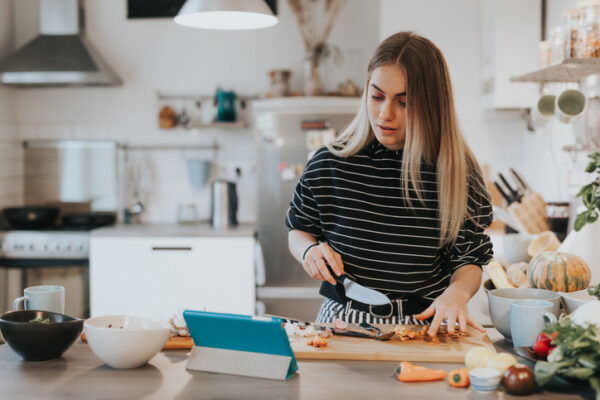 healthy teen girl cooking herself dinner while watching a video