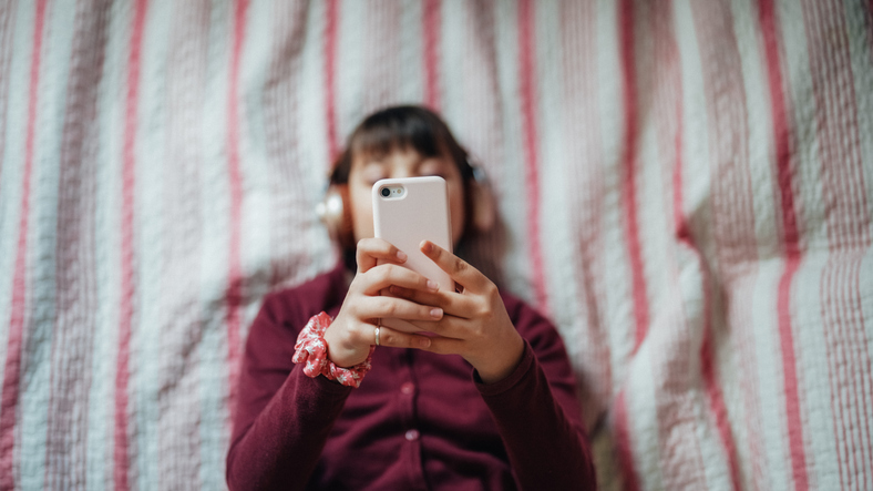 Girl in bed enjoying a good music from smartphone app