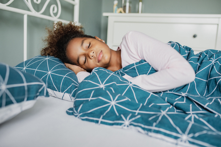 Girl sleeping in bed practicing good sleep hygiene