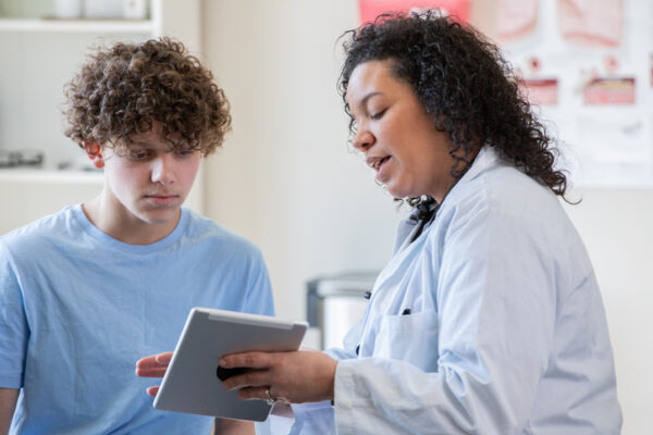 Doctor showing her teenage patient documents on her digital tablet.