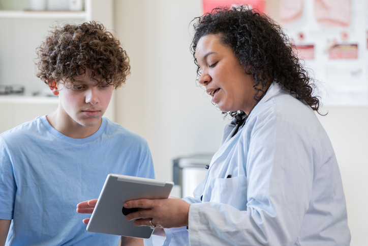 Doctor showing her teenage patient documents on her digital tablet.