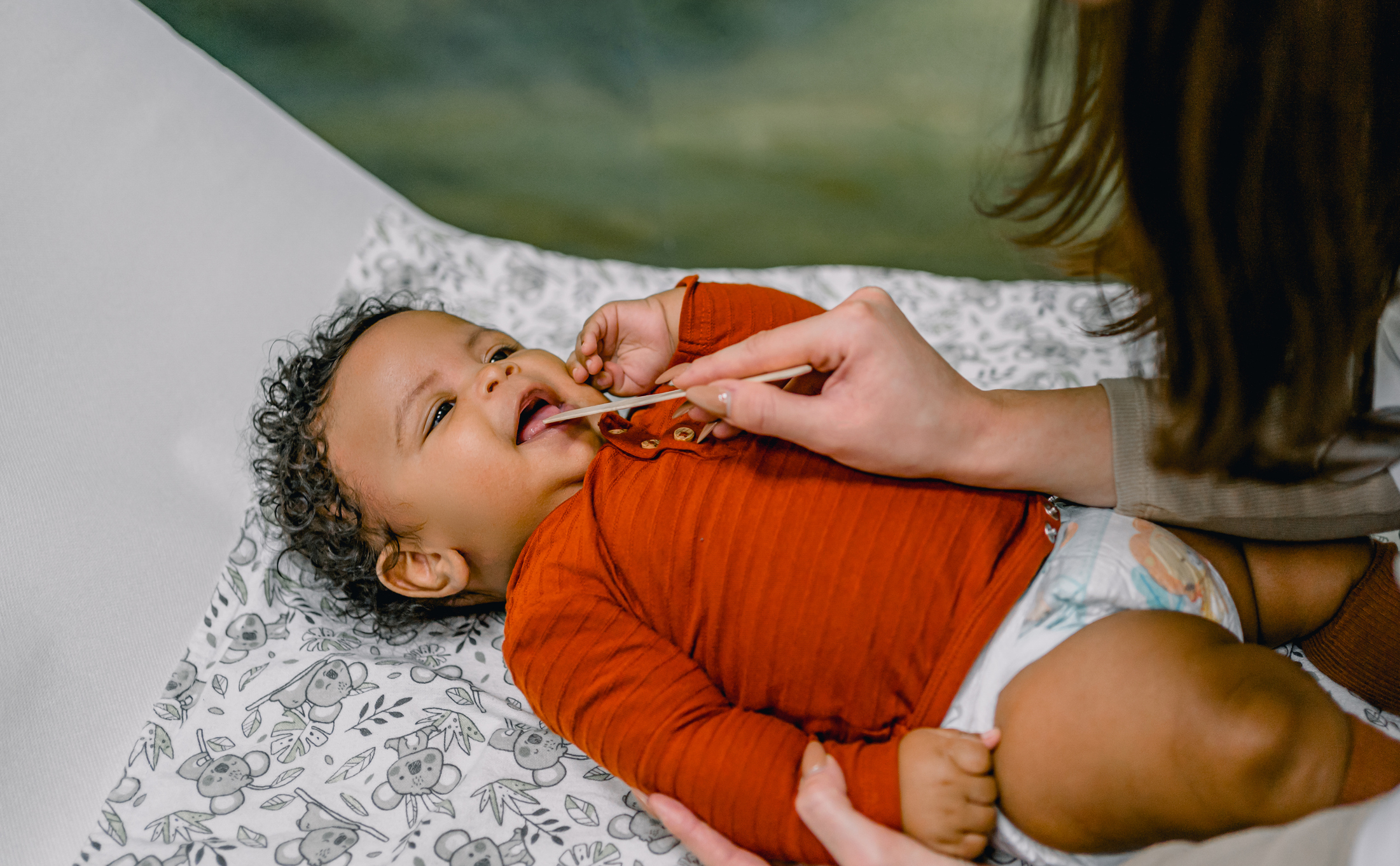 Pediatric ENT examining the mouth of a baby using a medical spatula in doctor's office to check for lip tie or tongue tie