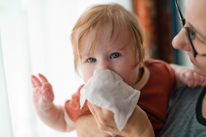 Mother helping her little child to clean nose to demonstrate possible symptom of RSV