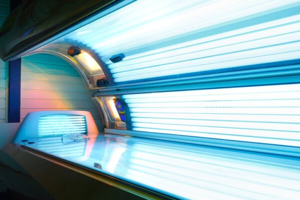 Opened running tanning bed with face tanner showing UV light exposure