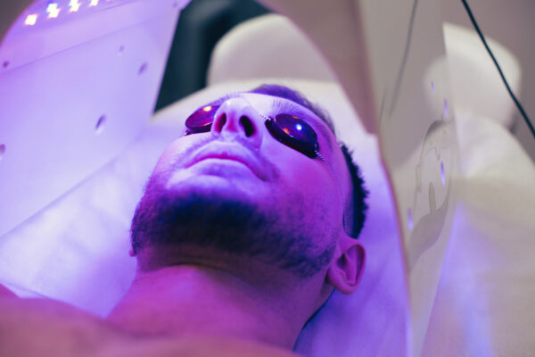Close up of a calm young man lying in a tanning bed and having protective glasses on his eyes to protect them from UV light