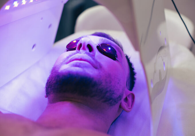 Close up of a calm young man lying in a tanning bed and having protective glasses on his eyes to protect them from UV light