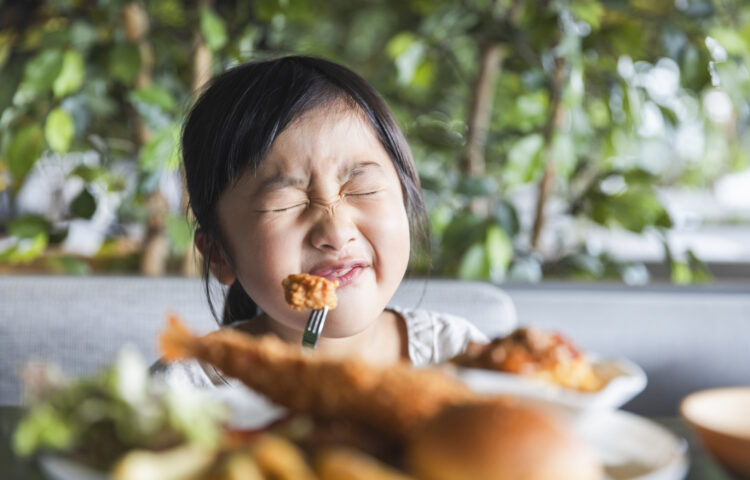 girl making a face while eating a vegetable