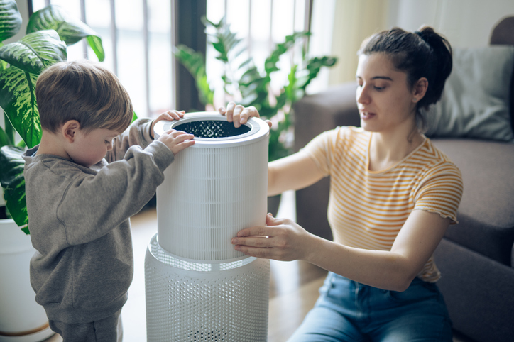 Mother and her child is changing new filter on air purifier to prevent asthma symptoms
