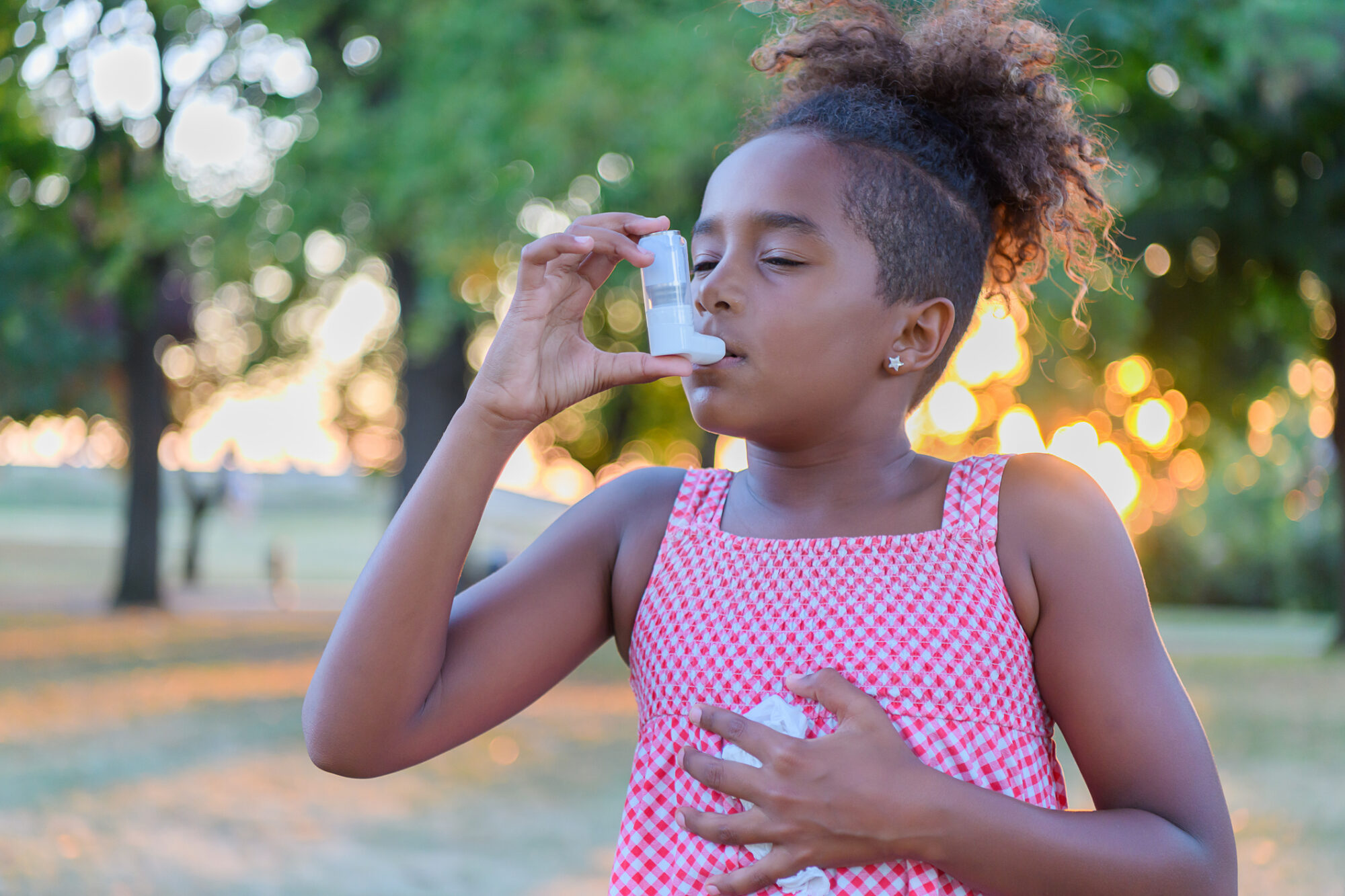 Young Girl is using inhaler for asthma symptom relief during Asthma Peak Week in September