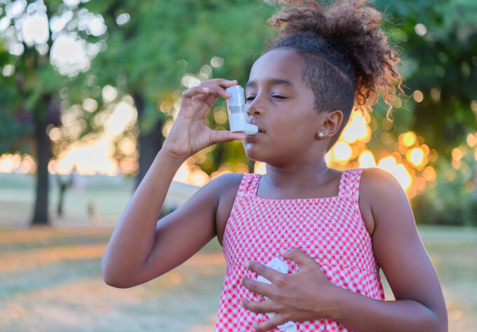 Young Girl is using inhaler for asthma symptom relief during Asthma Peak Week in September