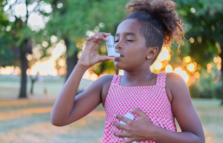 Young Girl is using inhaler for asthma symptom relief during Asthma Peak Week in September