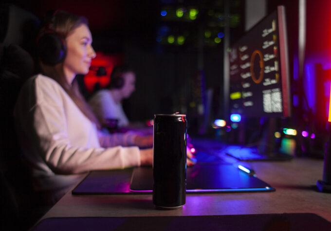 young girl gamer sits at a computer with a Feel Free kratom drink