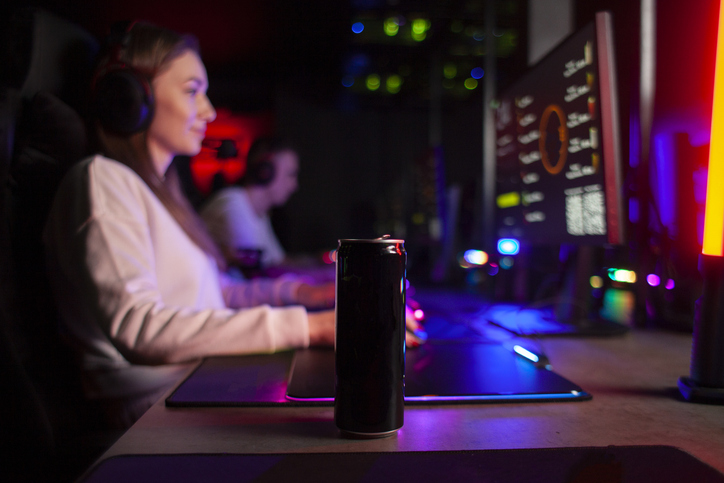 young girl gamer sits at a computer with a Feel Free kratom drink