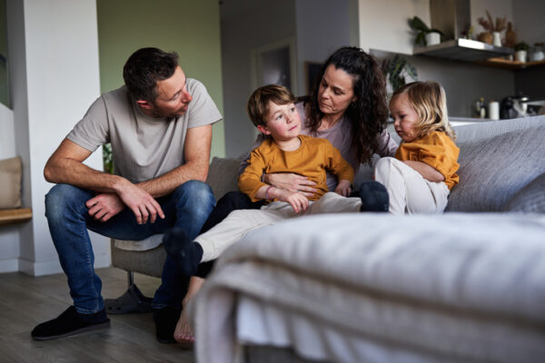 Family talking sitting on couch at home having conversations about cancer with children