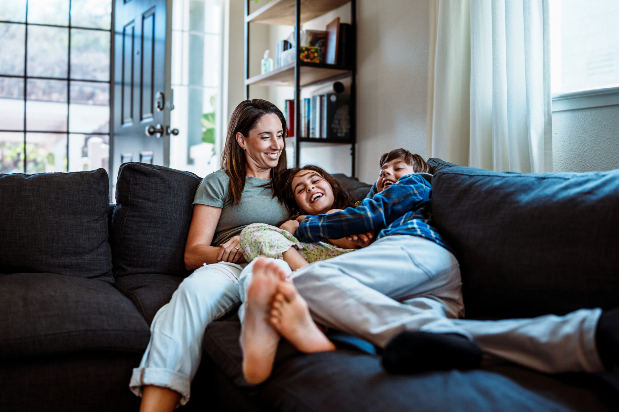 Playful, healthy kids on the couch with their mom during flu season