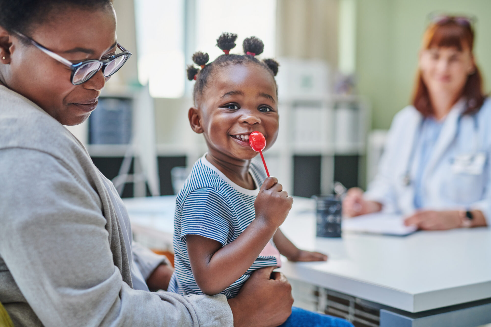 Little girl getting a lollipop from her doctor after a flu vaccine during a checkup