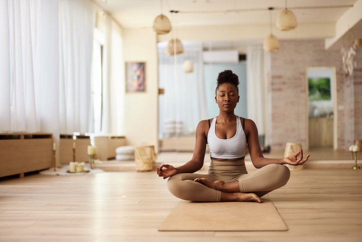 Young woman doing Yoga meditation exercises in Lotus position to prep body for pregnancy