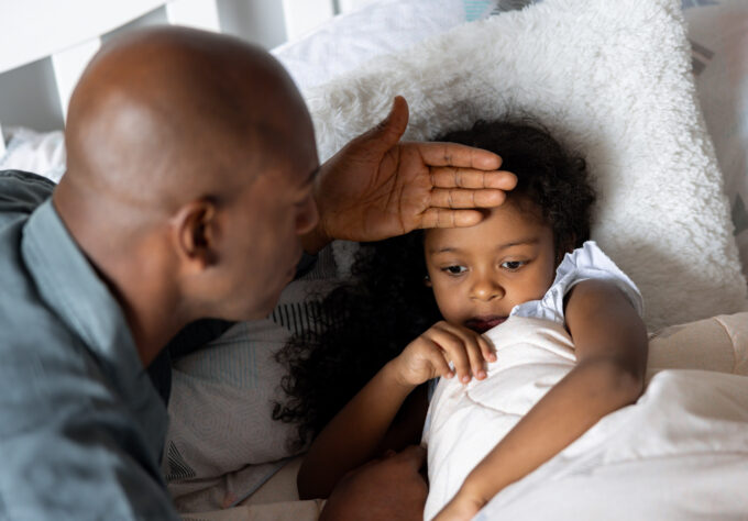 Father checking on his sick daughter at home who might have COVID, RSV, or the flu.