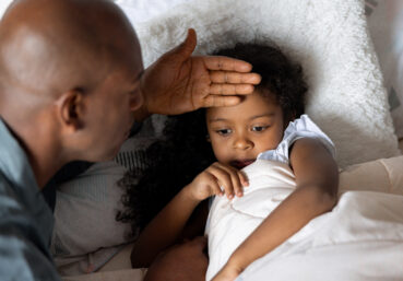 Father checking on his sick daughter at home who might have COVID, RSV, or the flu.