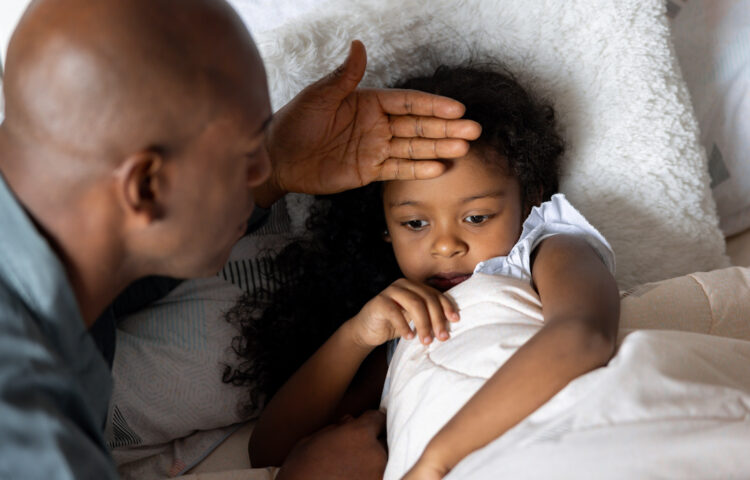 Father checking on his sick daughter at home who might have COVID, RSV, or the flu.