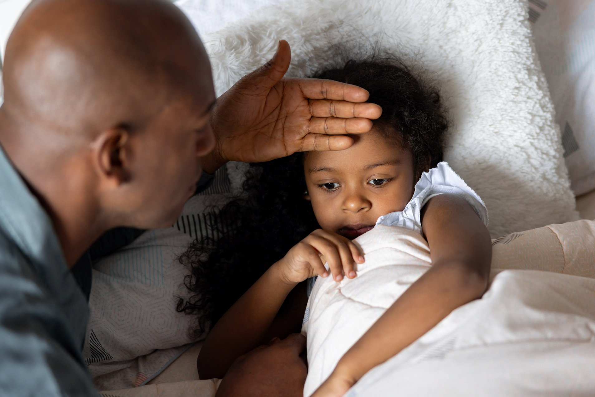 Father checking on his sick daughter at home who might have COVID, RSV, or the flu.