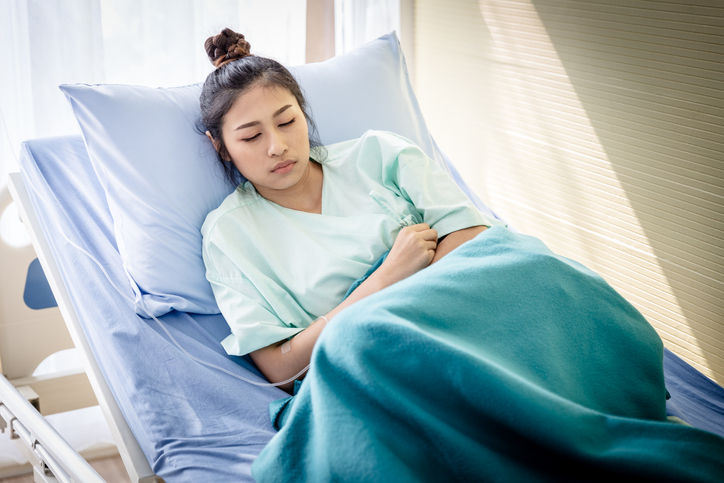 Women in hospital bed resting after treatment for to hyperemesis gravidarum, also referred to as HG