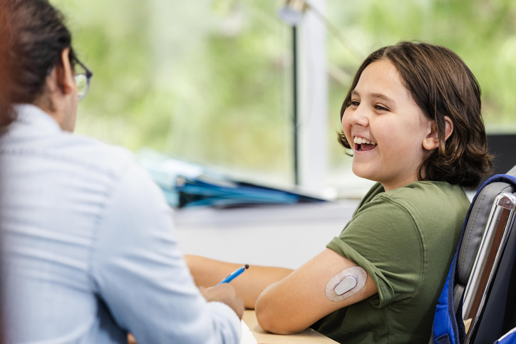 A school age boy with type 1 diabetes smiles while talking to his doctor