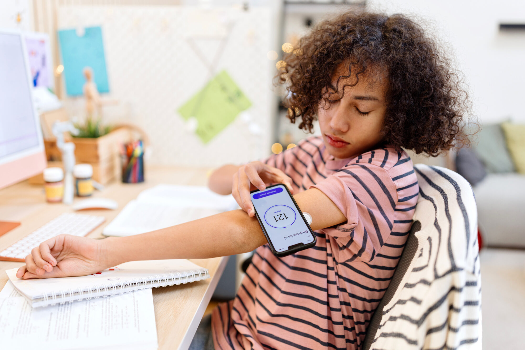 Teenager with type 1 diabetes using an app to check his sugar level at home while working on homework