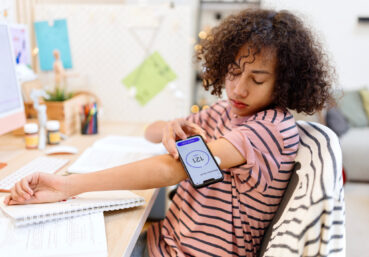 Teenager with type 1 diabetes using an app to check his sugar level at home while working on homework
