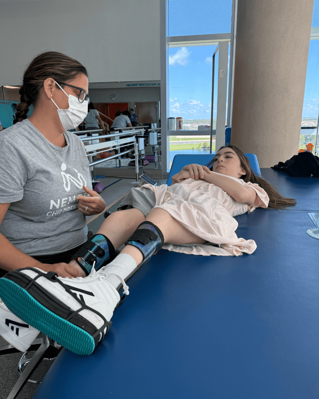 Teen girl with leg braces engages in physical therapy exercises during a rehab session.