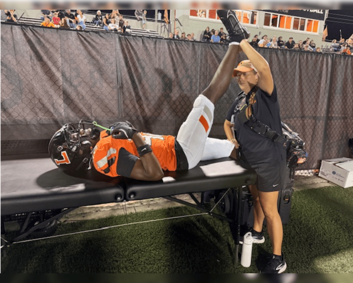 Athletic Trainer Stretches High School Football Player