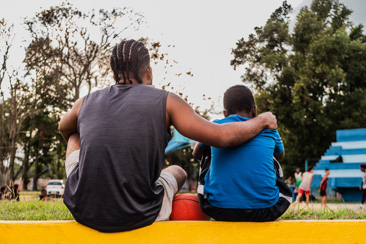 Father and son watching a basketball match while having a tough conversation about current events.