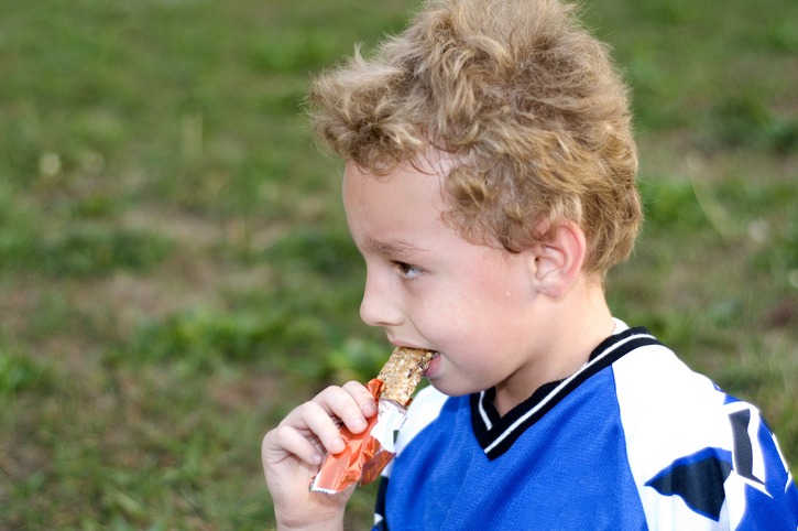 Soccer player eating halftime granola bar as snack before practice.