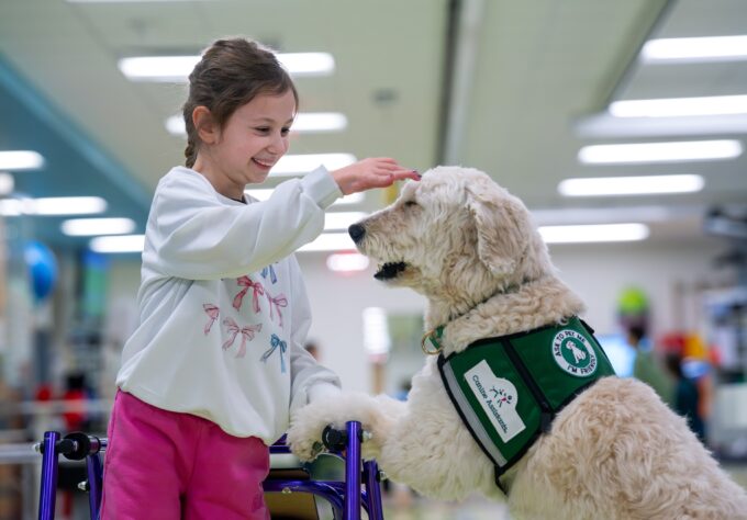 Child patient pets a facility dog during her stay and recovery at Nemours hospital.