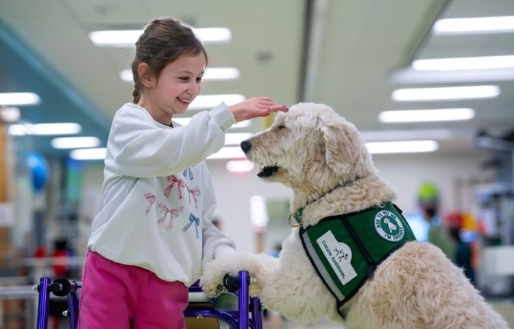 Child patient pets a facility dog during her stay and recovery at Nemours hospital.