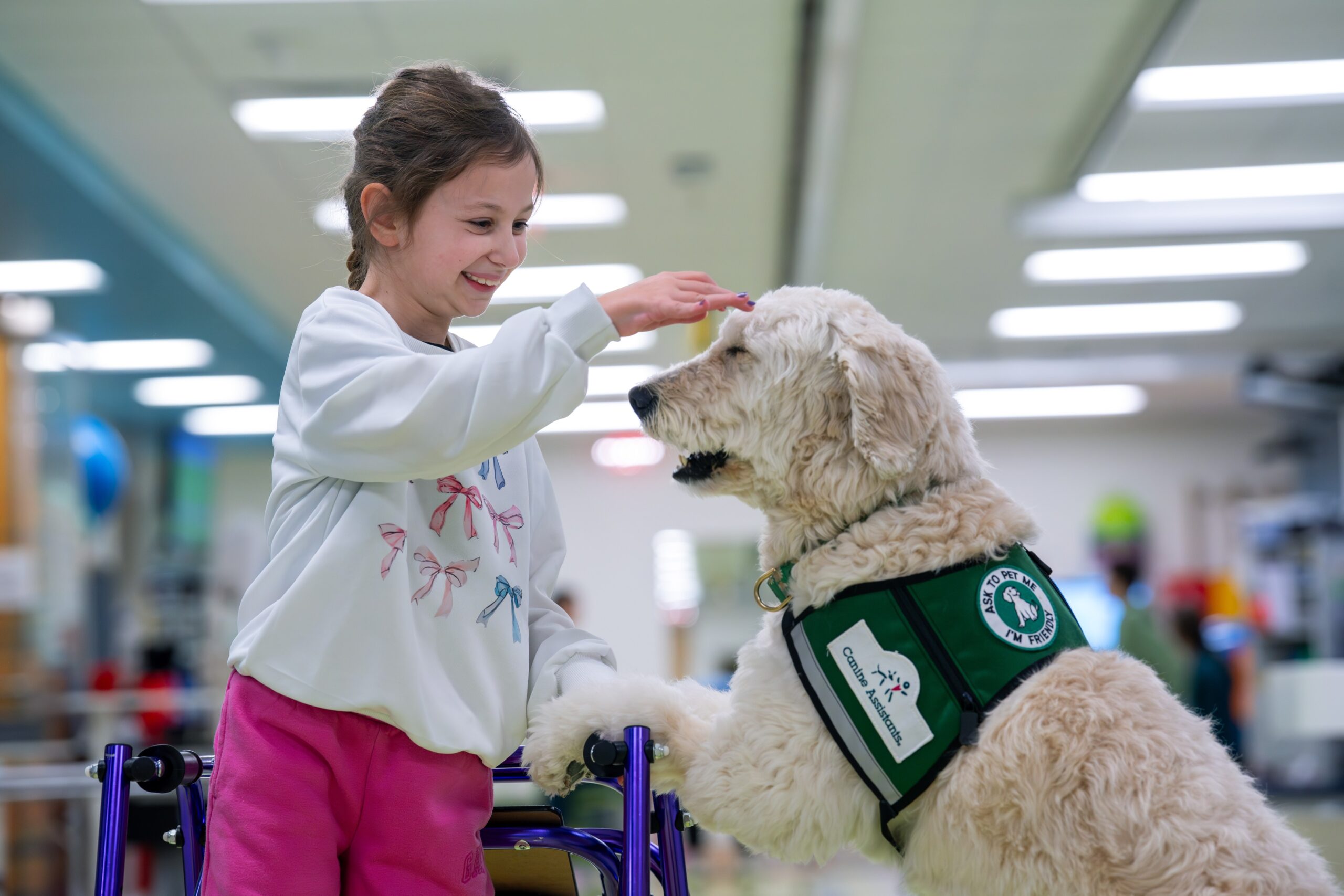 Child patient pets a facility dog during her stay and recovery at Nemours hospital.