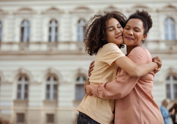 A Touching Portrait of a Mother and Her Teenage Son Sharing a Warm Hug Outdoors, Highlighting Their Close and Loving Relationship.