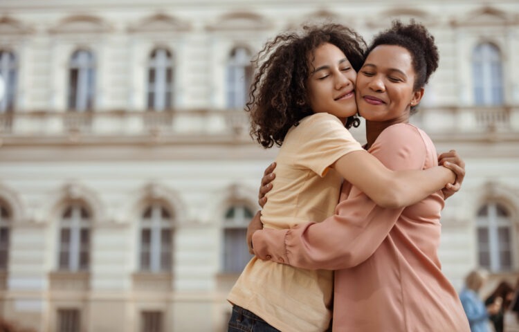 A Touching Portrait of a Mother and Her Teenage Son Sharing a Warm Hug Outdoors, Highlighting Their Close and Loving Relationship.