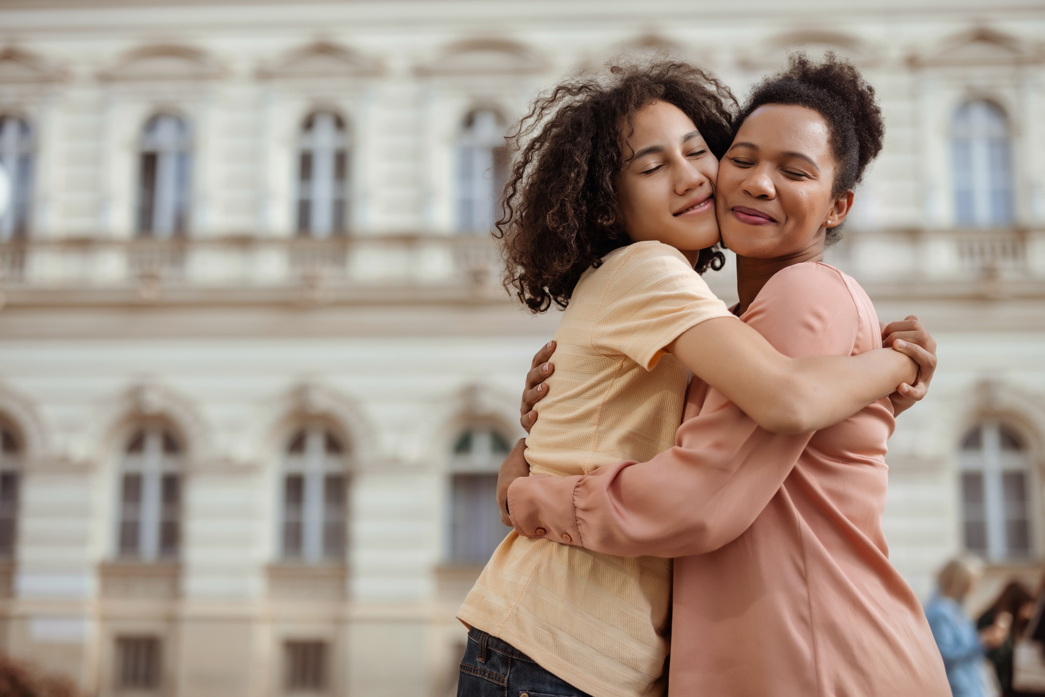 A Touching Portrait of a Mother and Her Teenage Son Sharing a Warm Hug Outdoors, Highlighting Their Close and Loving Relationship.