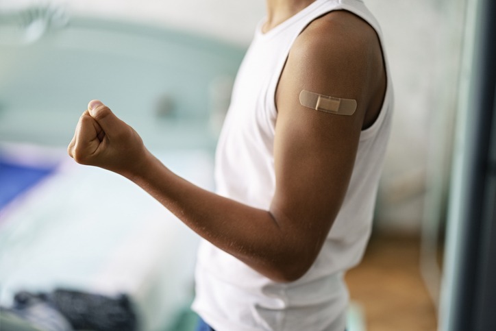 Portrait of a 12 years old teenage boy showing adhesive bandage. The boy has been vaccinated to protect against HPV.
