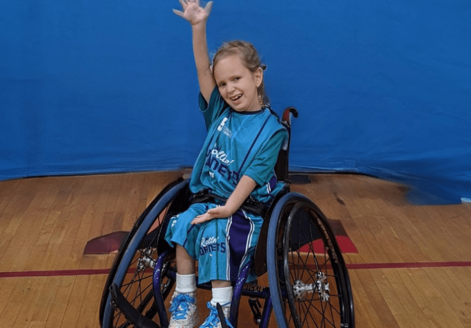 Girl playing wheelchair basketball smiles for a photo