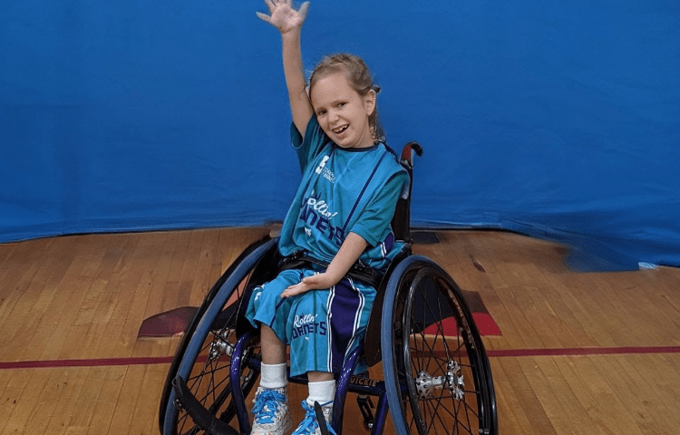 Girl playing wheelchair basketball smiles for a photo