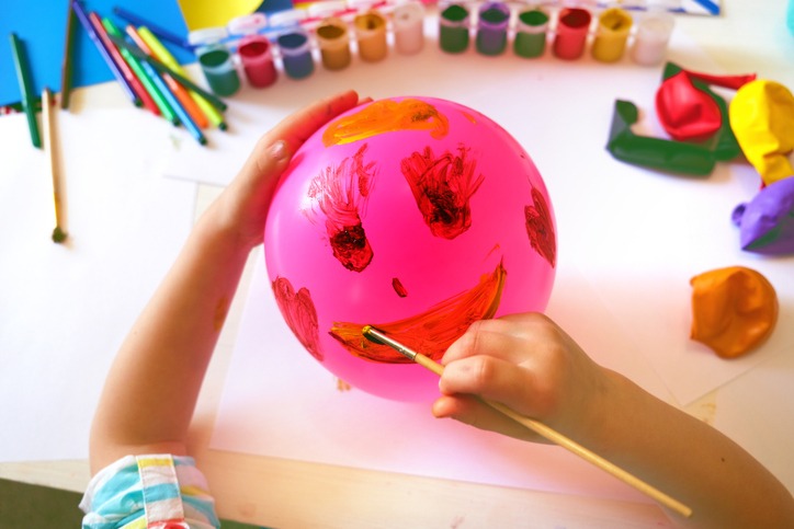 Child drawing pattern of paints fun smile on the balloon.