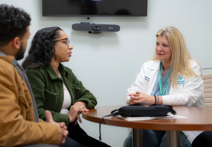 Mother and father are speaking with a genetic counselor about prenatal testing.